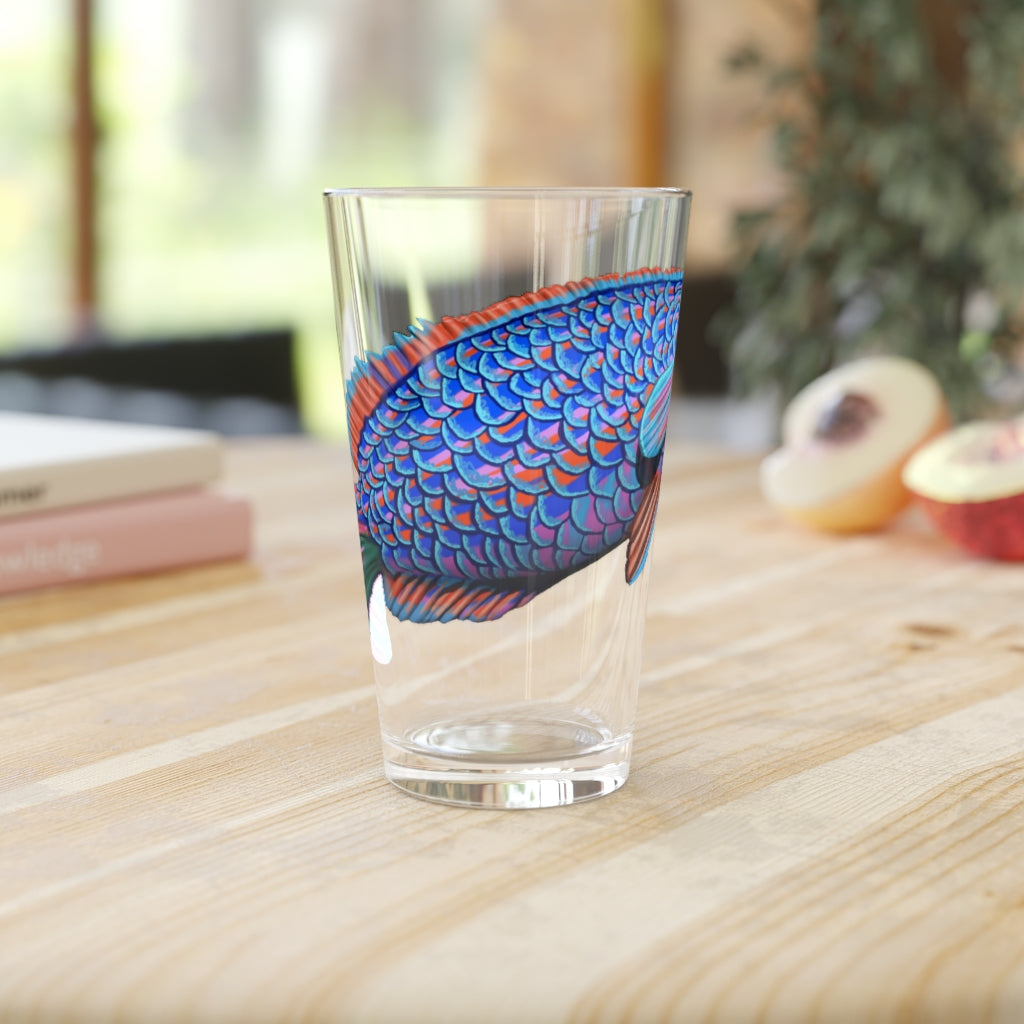 A clear 16oz pint glass featuring a vibrant blue and purple fish design, perfect for enjoying beverages.