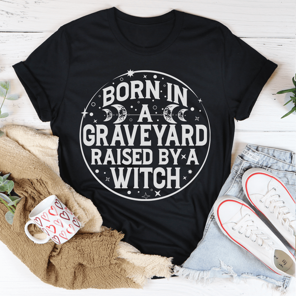 Born In A Graveyard Raised By A Witch T-Shirt displayed on a mannequin, showcasing its unique design and soft fabric.