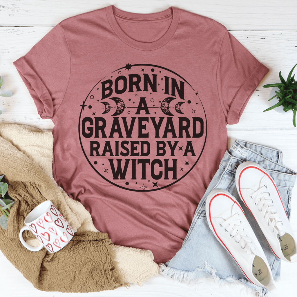 Born In A Graveyard Raised By A Witch T-Shirt displayed on a mannequin, showcasing its unique design and soft fabric.