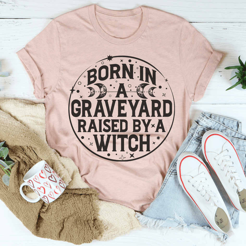 Born In A Graveyard Raised By A Witch T-Shirt displayed on a mannequin, showcasing its unique design and soft fabric.