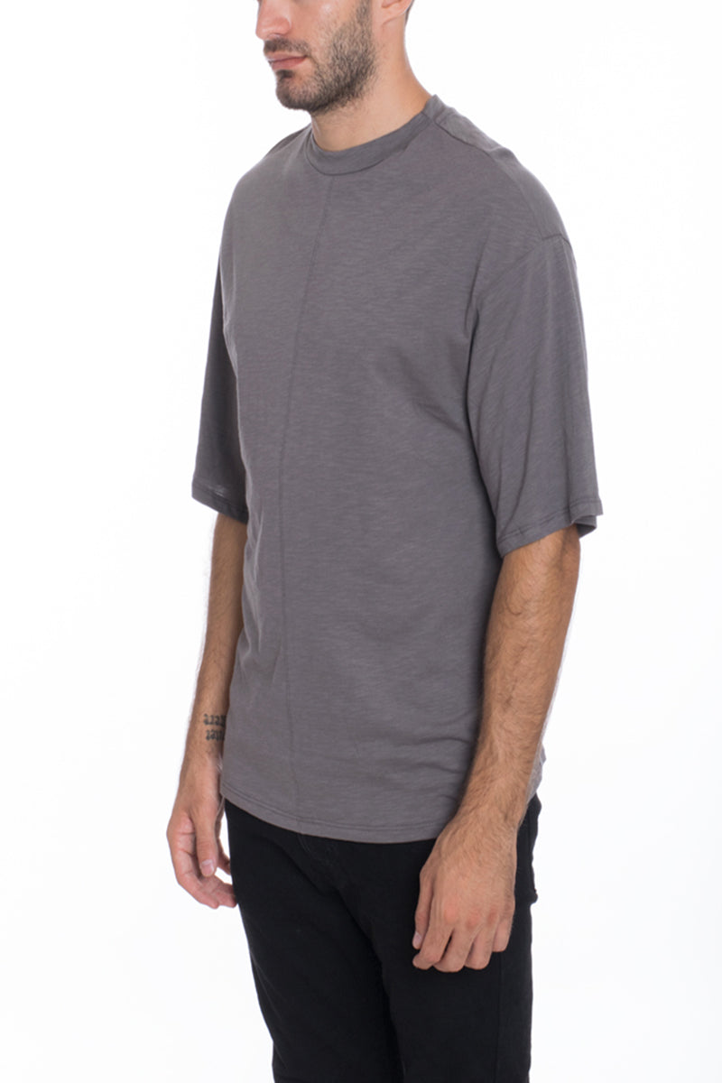 A stylish Box Tee made of 100% cotton, featuring a center seam and elbow-length sleeves, displayed on a model.