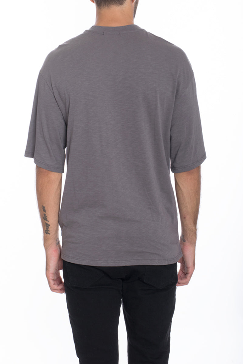 A stylish Box Tee made of 100% cotton, featuring a center seam and elbow-length sleeves, displayed on a model.