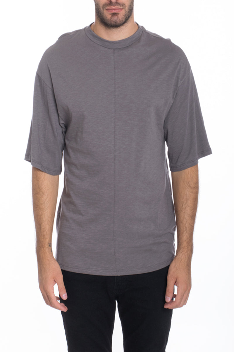 A stylish Box Tee made of 100% cotton, featuring a center seam and elbow-length sleeves, displayed on a model.