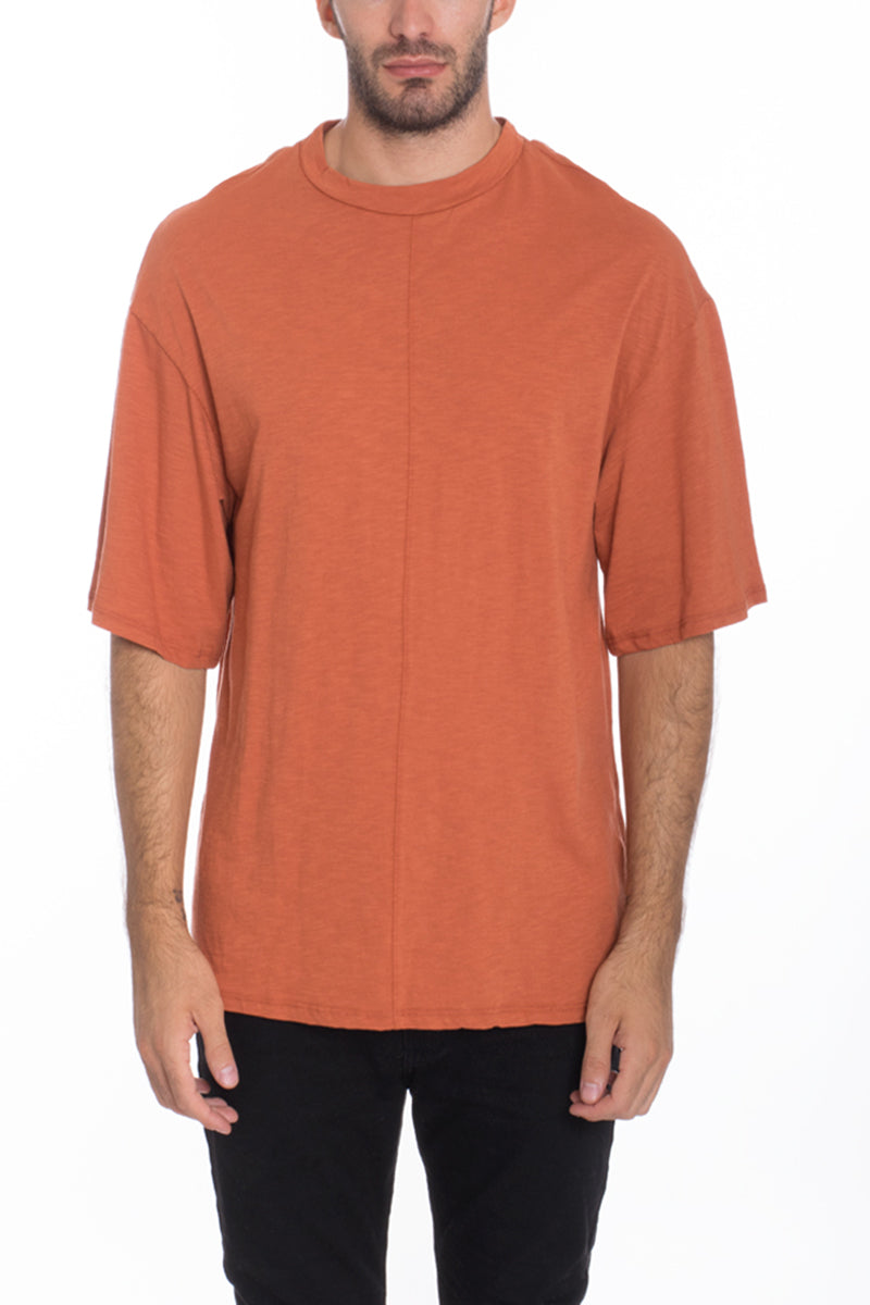 A stylish Box Tee made of 100% cotton, featuring a center seam and elbow-length sleeves, displayed on a model.