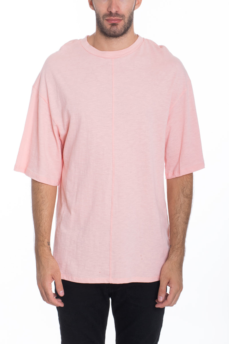 A stylish Box Tee made of 100% cotton, featuring a center seam and elbow-length sleeves, displayed on a model.