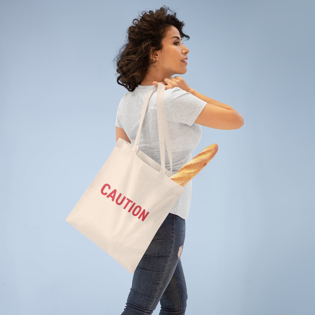 Caution Tote Bag made of 100% cotton with long handles and cross-stitched detailing, available in multiple colors.