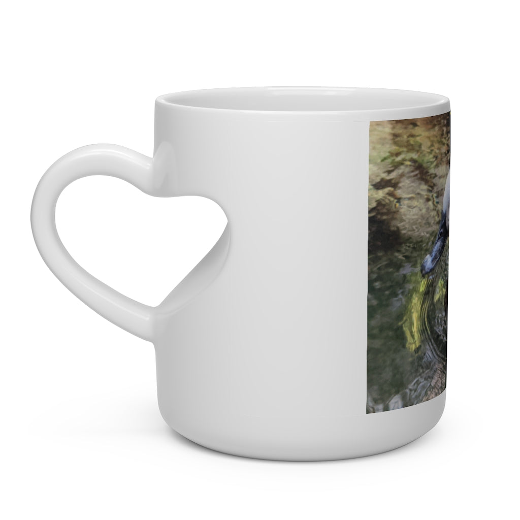 A charming white ceramic mug shaped like a heart with a heart-shaped handle, perfect for hot beverages.