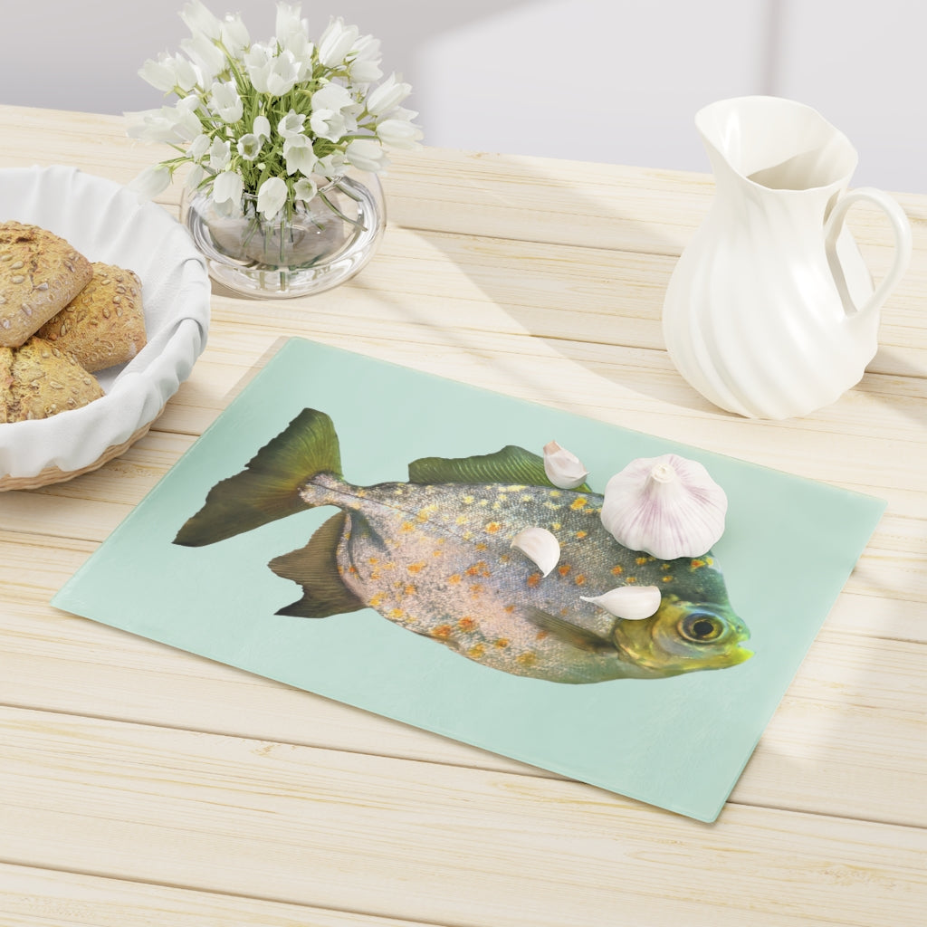 A stylish Fish with Specs Cutting Board made of tempered glass, featuring a unique fish design and four rubber dots for stability.