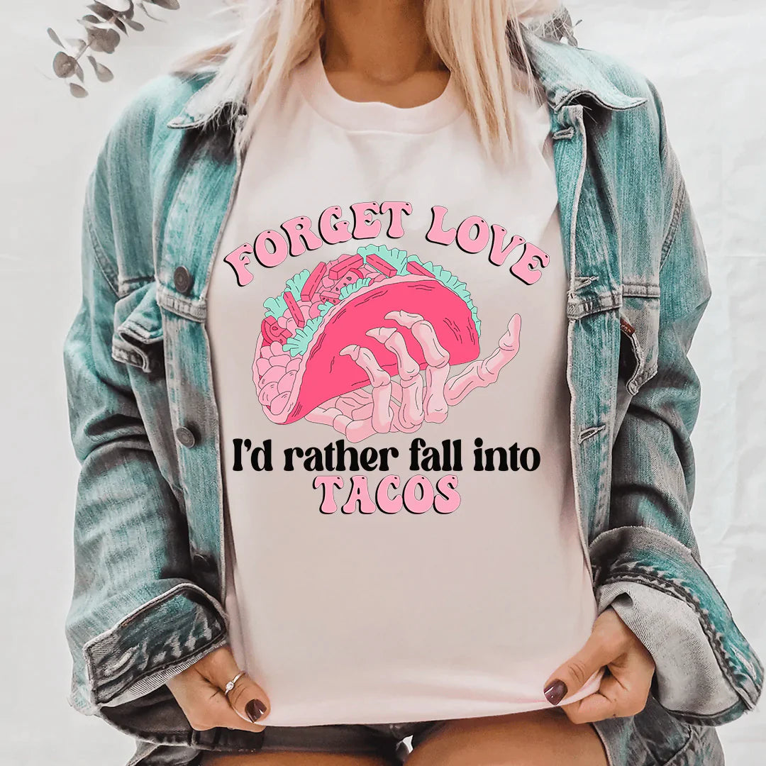 A humorous t-shirt featuring the phrase 'Forget Love I'd Rather Fall Into Tacos', made from soft cotton with double stitching.