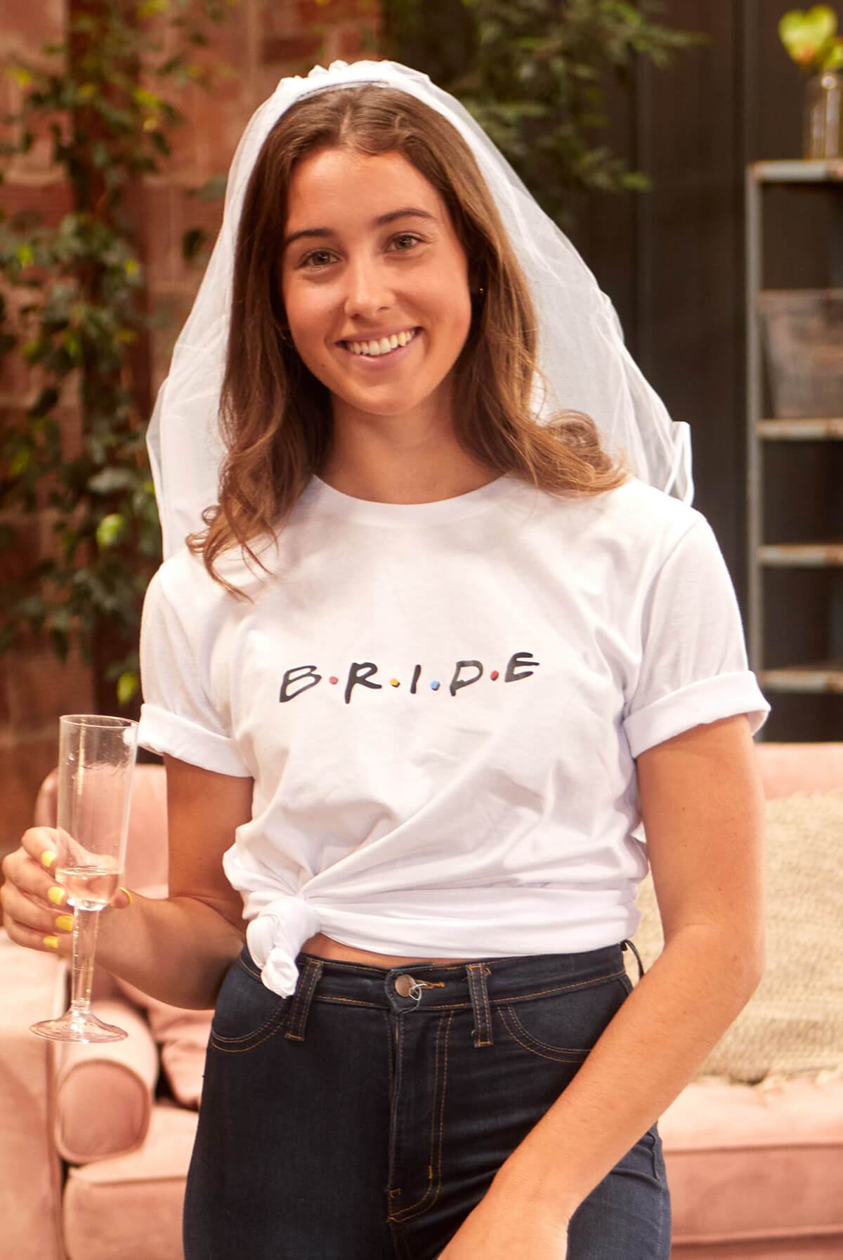 Two FRIENDS-themed tees for brides and amigas, one white with 'B.R.I.D.E' and one pink with 'A.M.I.G.A.S', displayed together.