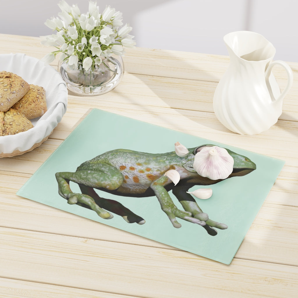 A vibrant frog-themed tempered glass cutting board with rubber dots for stability, perfect for kitchen use.