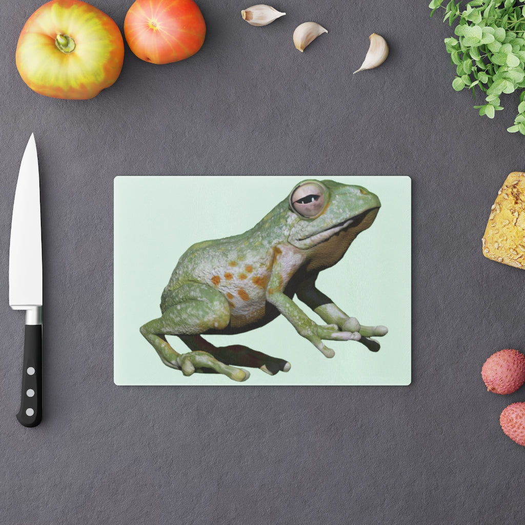 A vibrant frog-themed tempered glass cutting board with rubber dots for stability, perfect for kitchen use.