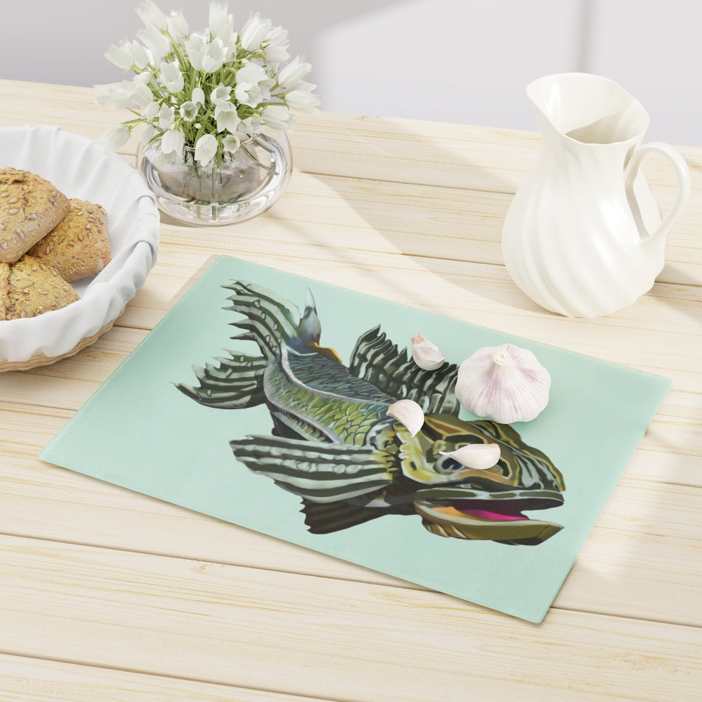 A stylish green fish cutting board made of tempered glass, featuring a unique fish design and four rubber dots for stability.