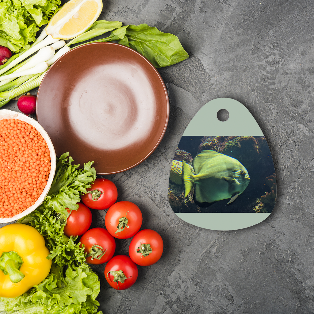 A round green fish sublimation glass cutting board with a toughened surface, featuring a vibrant design and four rubber feet for stability.