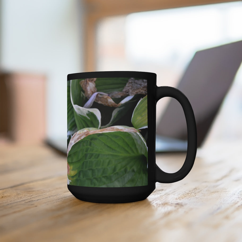 A stylish 15oz black ceramic mug featuring green leaves design, perfect for coffee and tea lovers.