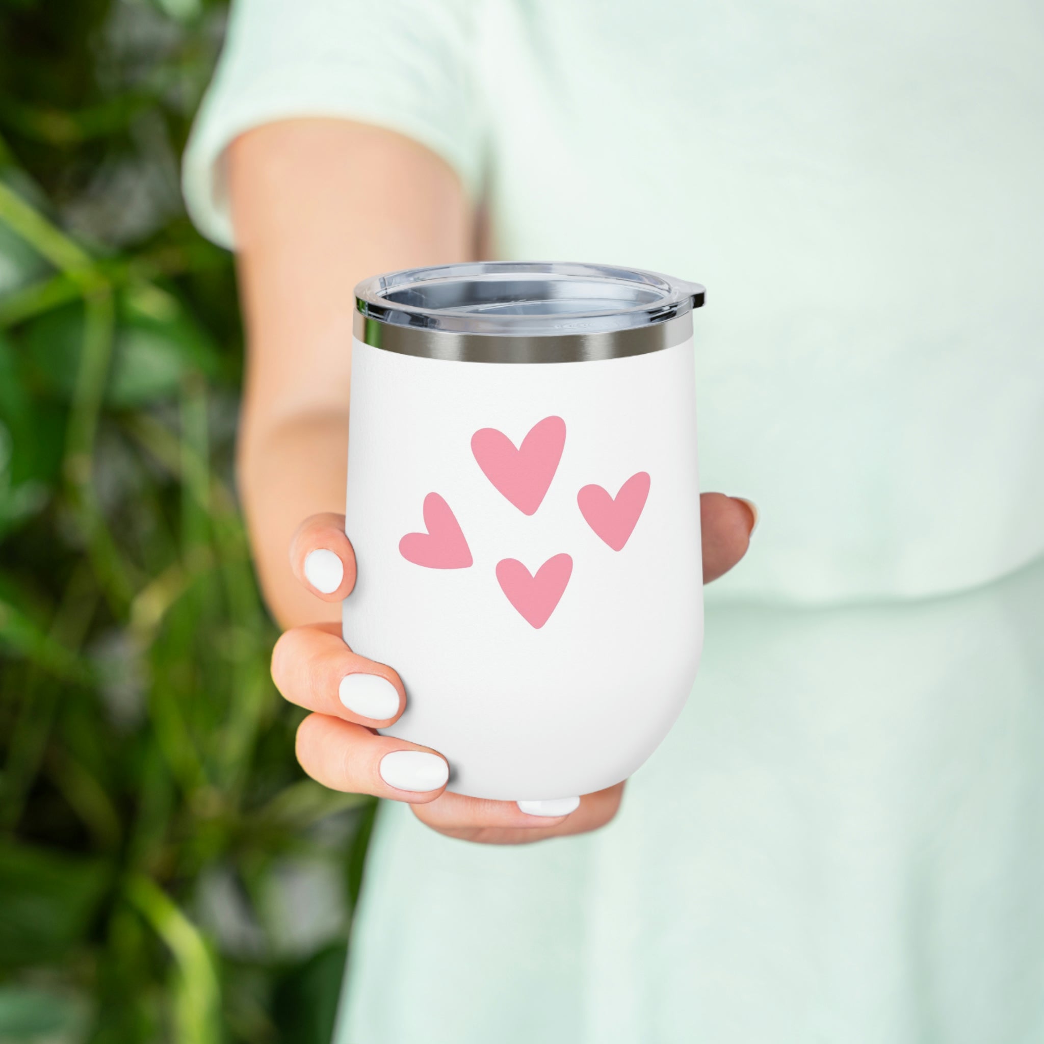 A stylish Hearts Wine Tumbler made of stainless steel with a clear plastic lid, perfect for hot and cold beverages.