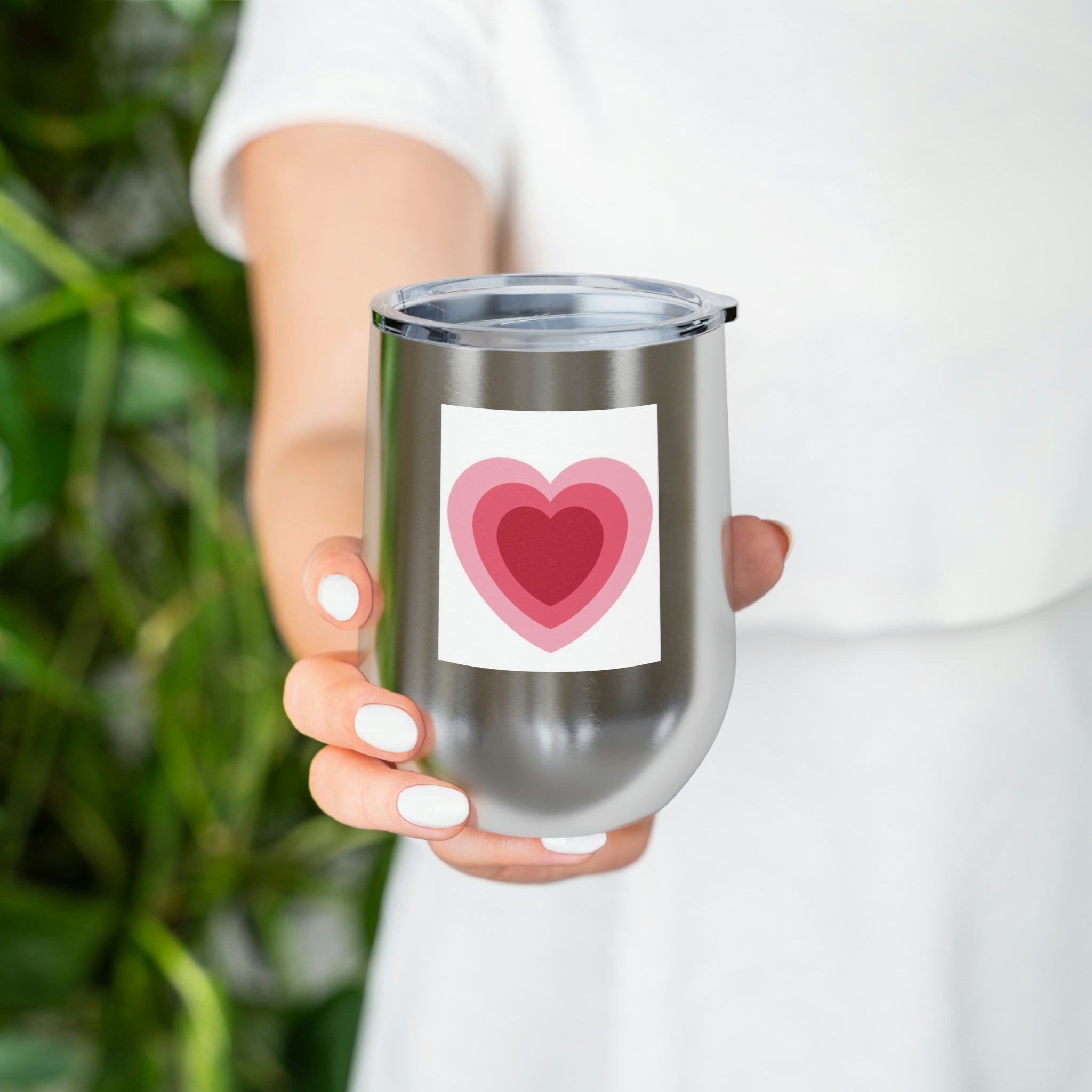 A stylish Hearts Wine Tumbler made of stainless steel with a clear plastic lid, perfect for hot and cold beverages.