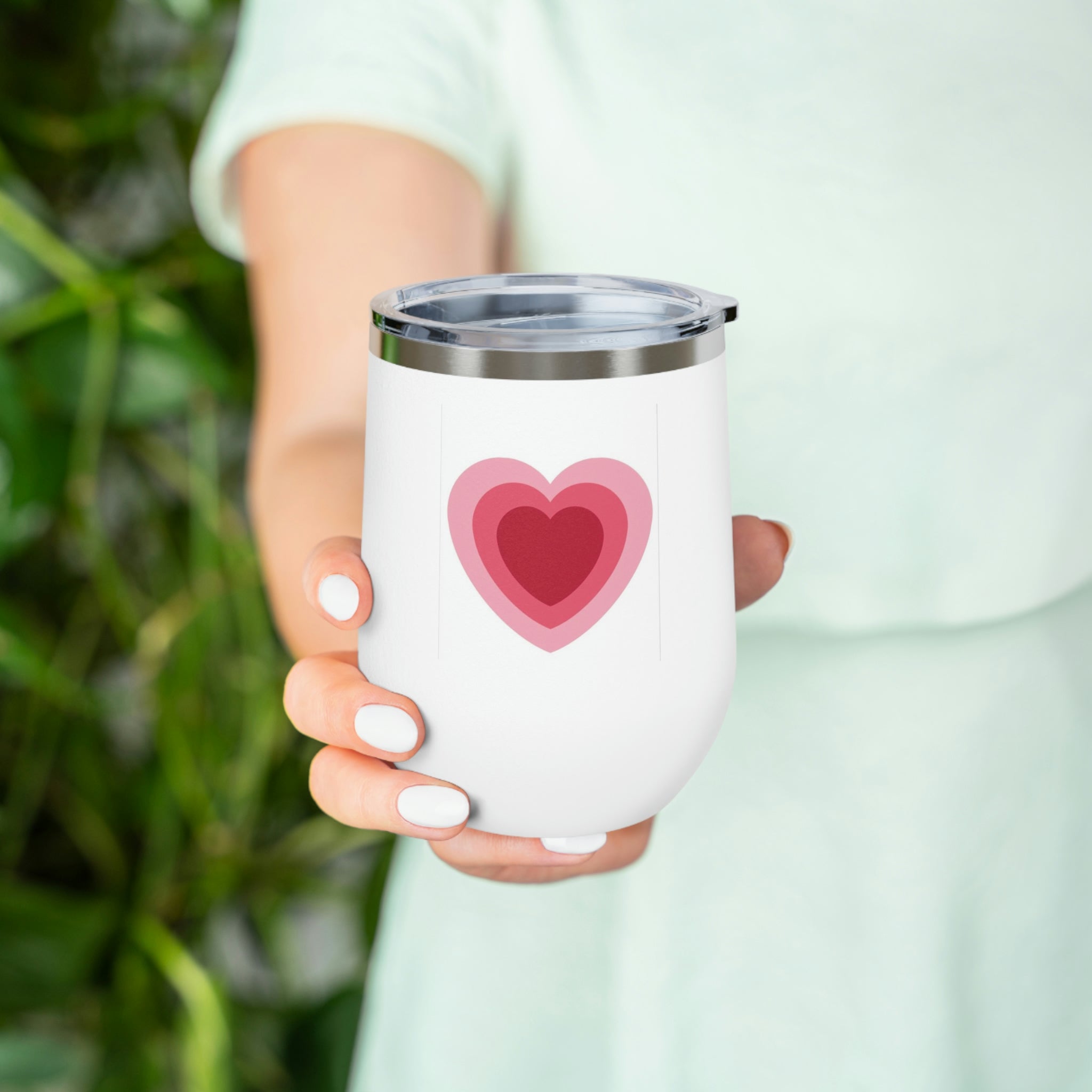 A stylish Hearts Wine Tumbler made of stainless steel with a clear plastic lid, perfect for hot and cold beverages.