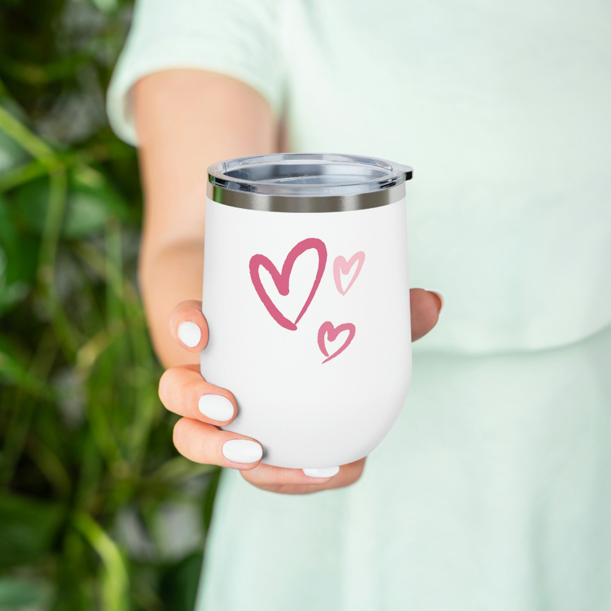 A stylish Hearts Wine Tumbler made of stainless steel with a clear plastic lid, showcasing a heart design, perfect for hot and cold beverages.