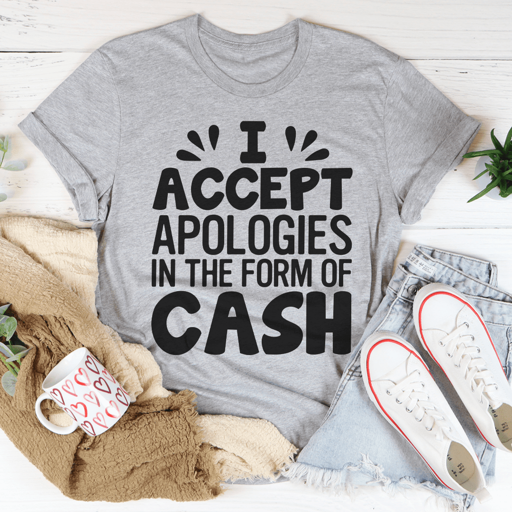 A humorous t-shirt featuring the phrase 'I Accept Apologies In The Form Of Cash', made from soft cotton with double stitching.