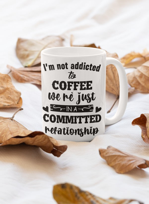 A glossy 11oz coffee mug with the phrase 'I Am Not Addicted To Coffee' printed on it, featuring a sturdy handle.