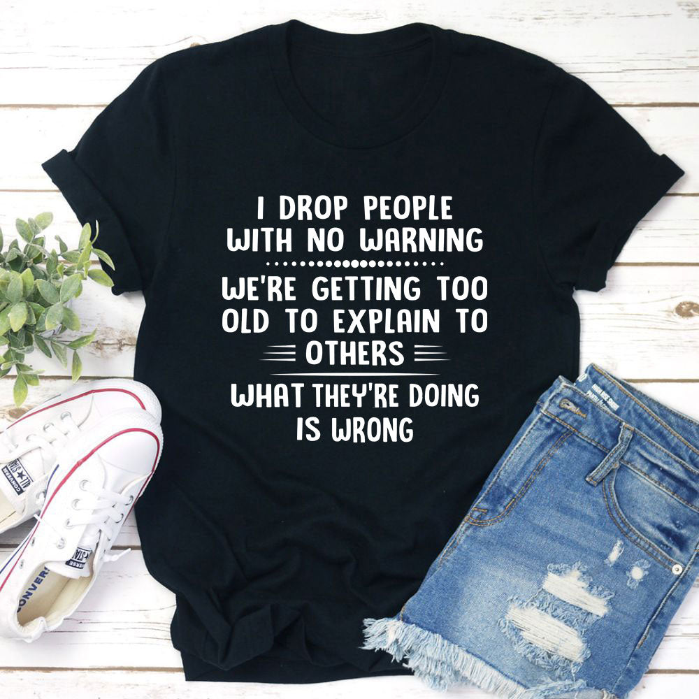 I Drop People With No Warning T-Shirt featuring bold text on a soft cotton fabric, showcasing its durability and comfort.