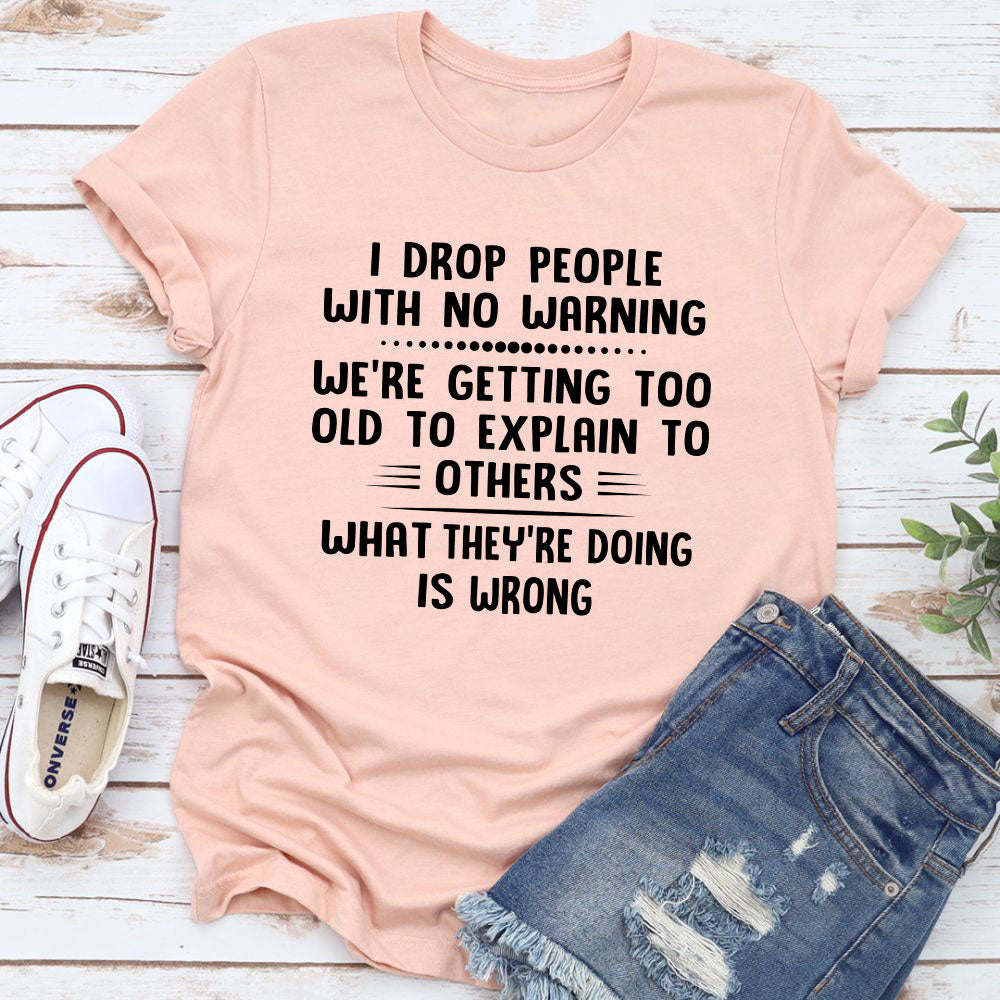 I Drop People With No Warning T-Shirt featuring bold text on a soft cotton fabric, showcasing its durability and comfort.