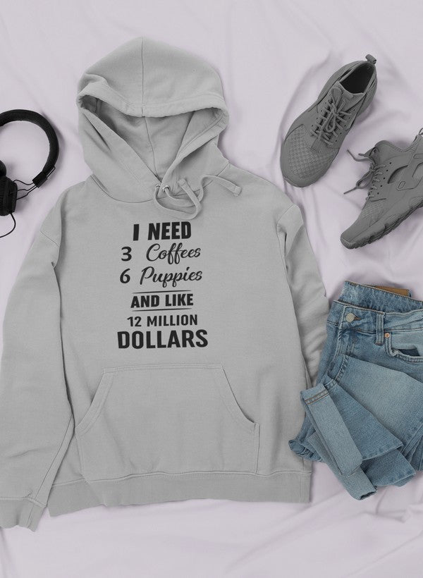 A cozy hoodie featuring the phrase 'I Need 3 Coffees 6 Puppies And Like 12 Million Dollars' designed for comfort and style.