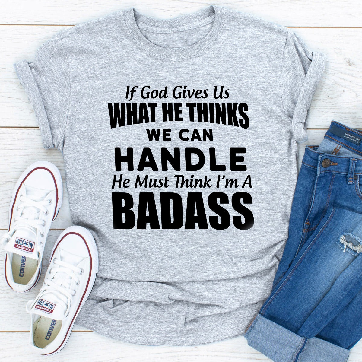 A stylish black t-shirt featuring the phrase 'If God Give Us What He Think We Can Handle He Must Think I'm A Badass' in bold lettering.