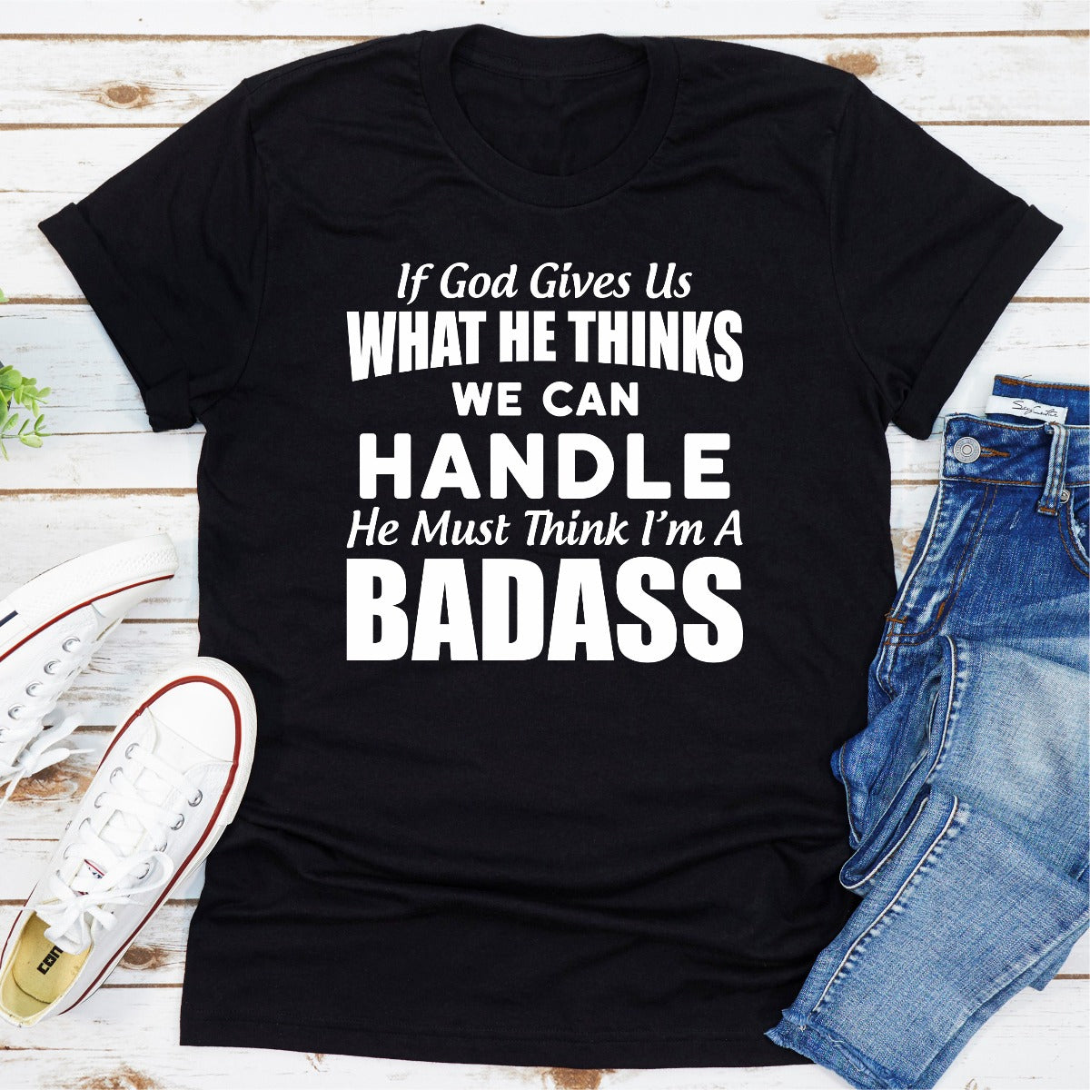 A stylish black t-shirt featuring the phrase 'If God Give Us What He Think We Can Handle He Must Think I'm A Badass' in bold lettering.