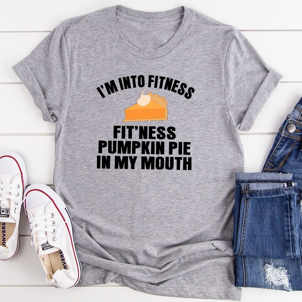 A humorous t-shirt featuring the phrase 'I'm Into Fitness... Fit'ness Pumpkin Pie In My Mouth' printed on a soft cotton fabric.