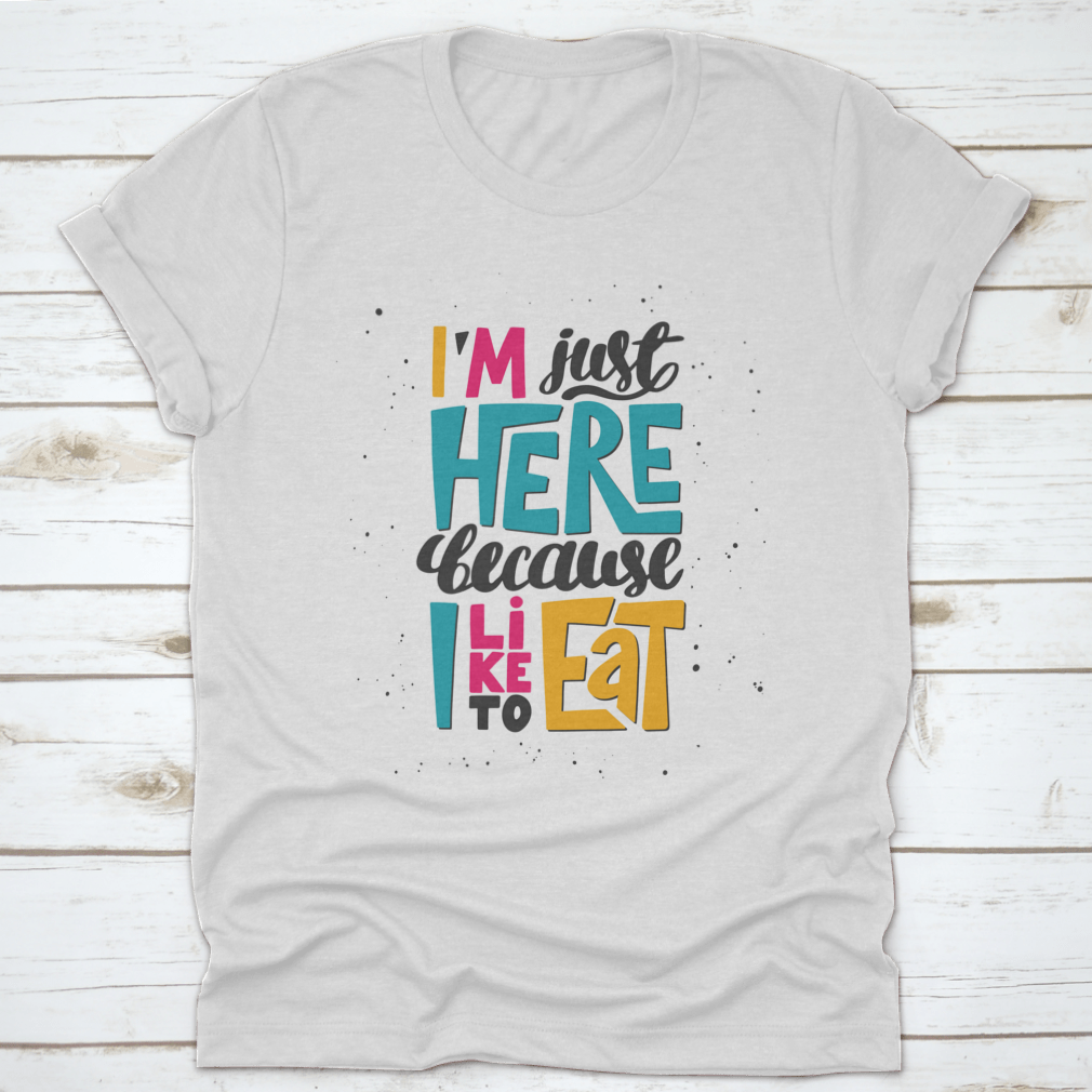 A comfortable I'M Just Here Because I Like To Eat Quote Design T-Shirt displayed on a hanger, showcasing its soft fabric and humorous quote.