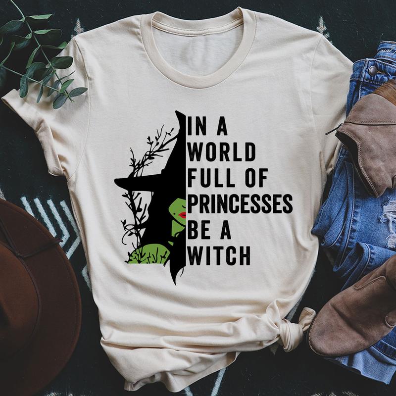 A stylish black t-shirt featuring the phrase 'In A World Full Of Princesses Be A Witch' in bold lettering, showcasing its comfortable fit and quality fabric.