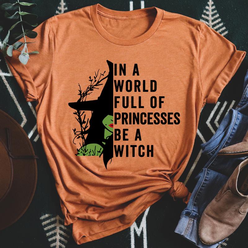 A stylish black t-shirt featuring the phrase 'In A World Full Of Princesses Be A Witch' in bold lettering, showcasing its comfortable fit and quality fabric.