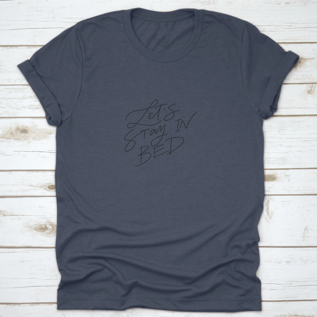 A cozy shirt featuring 'Let's Stay In Bed' vector hand lettering typography, made from 100% cotton for ultimate comfort.