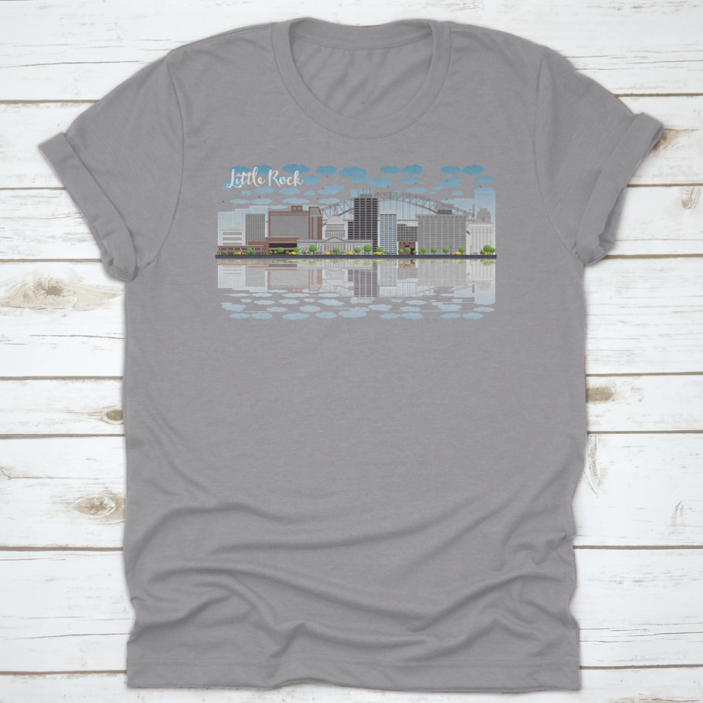 A stylish T-shirt featuring the Little Rock skyline with a grey building, blue sky, and reflections, showcasing urban beauty.