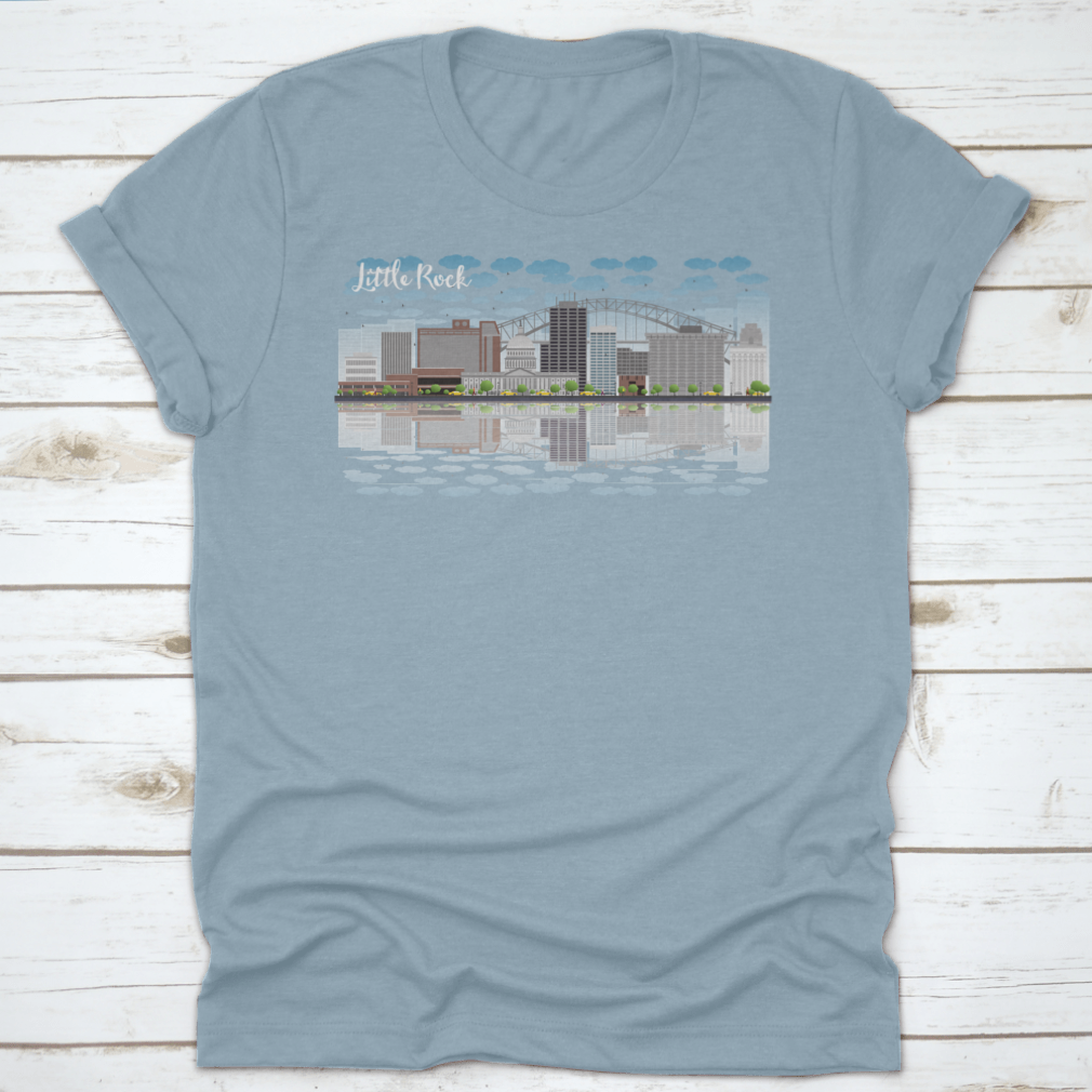 A stylish T-shirt featuring the Little Rock skyline with a grey building, blue sky, and reflections, showcasing urban beauty.