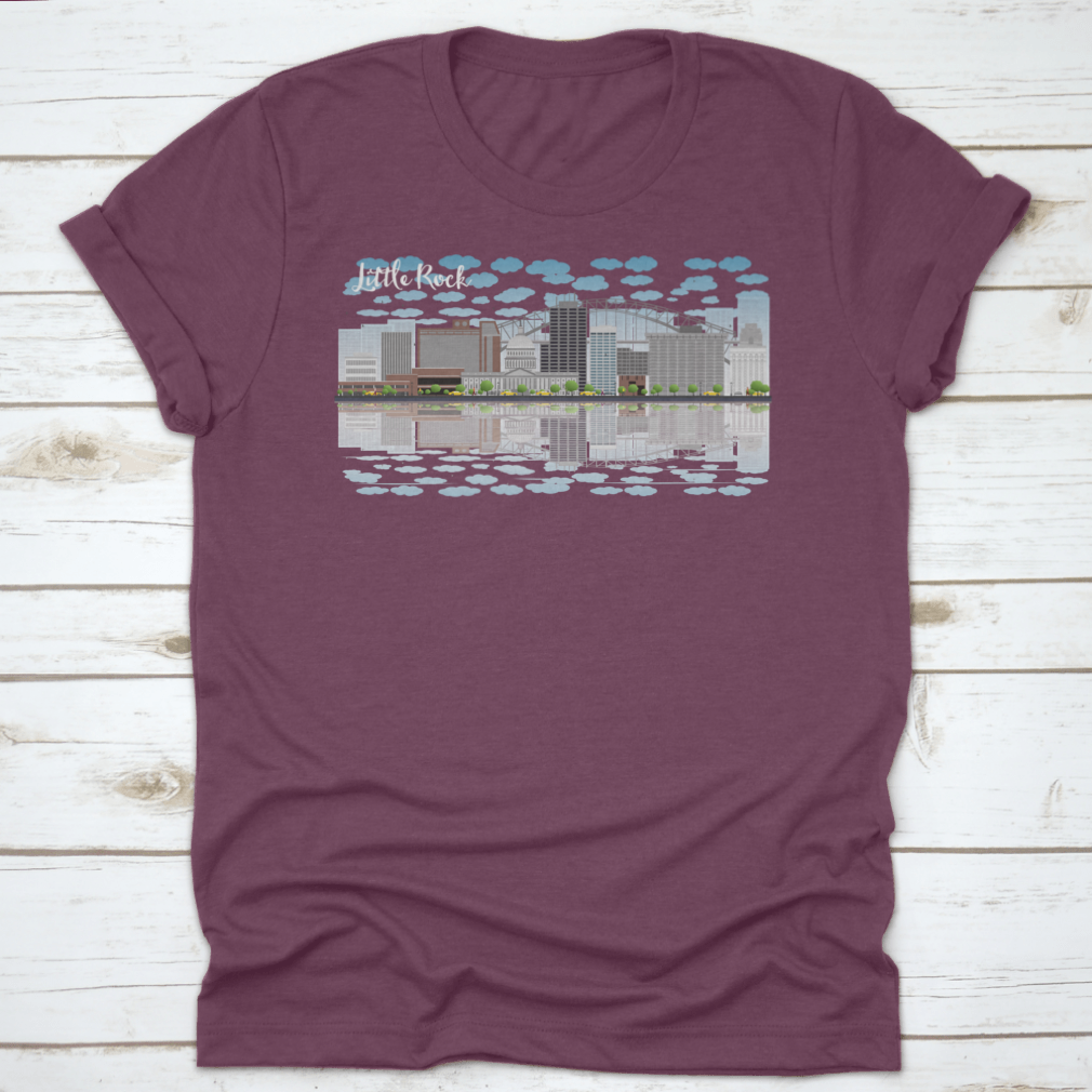 A stylish T-shirt featuring the Little Rock skyline with a grey building, blue sky, and reflections, showcasing urban beauty.