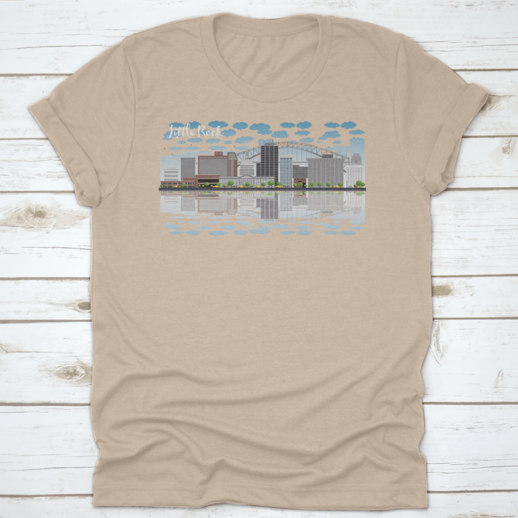 A stylish T-shirt featuring the Little Rock skyline with a grey building, blue sky, and reflections, showcasing urban beauty.