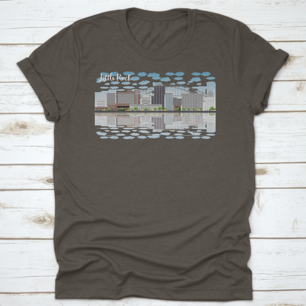 A stylish T-shirt featuring the Little Rock skyline with a grey building, blue sky, and reflections, showcasing urban beauty.