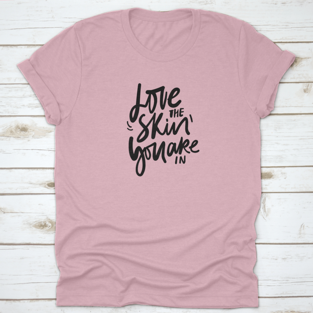 A stylish calligraphic shirt design featuring the quote 'Love Your Skin You Are In', made from soft cotton fabric.