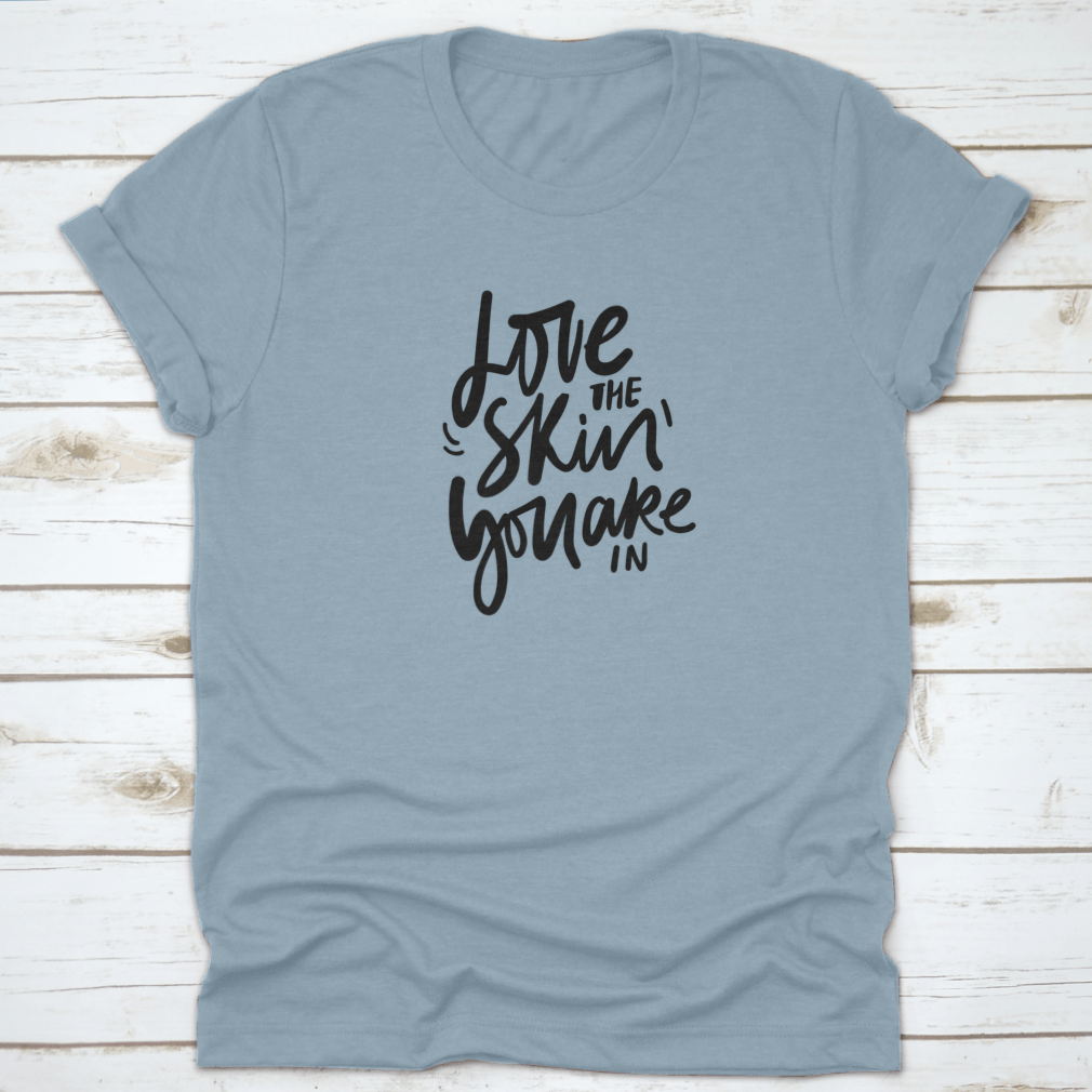 A stylish calligraphic shirt design featuring the quote 'Love Your Skin You Are In', made from soft cotton fabric.