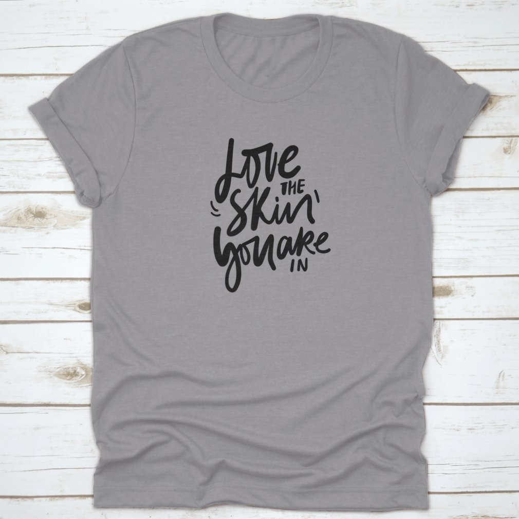 A stylish calligraphic shirt design featuring the quote 'Love Your Skin You Are In', made from soft cotton fabric.