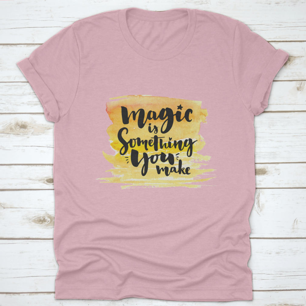 A vibrant yellow watercolor background featuring the phrase 'Magic Is Something You Make' in elegant brush lettering, showcasing creativity and artistic expression.