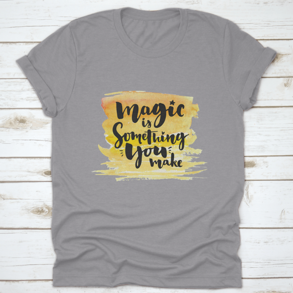 A vibrant yellow watercolor background featuring the phrase 'Magic Is Something You Make' in elegant brush lettering, showcasing creativity and artistic expression.