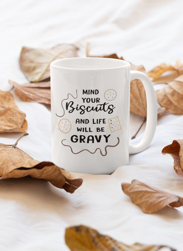 A stylish 11oz ceramic mug with a humorous phrase 'Mind Your Biscuits And Life Will Be Gravy' printed on it, featuring a glossy finish and sturdy handle.