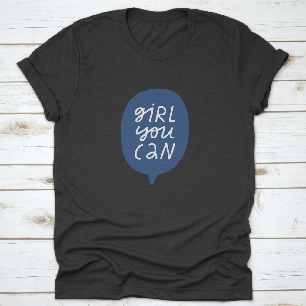 A stylish t-shirt featuring minimalist hand-drawn lettering in a blue speech bubble that reads 'Girl You Can', showcasing a casual and empowering design.