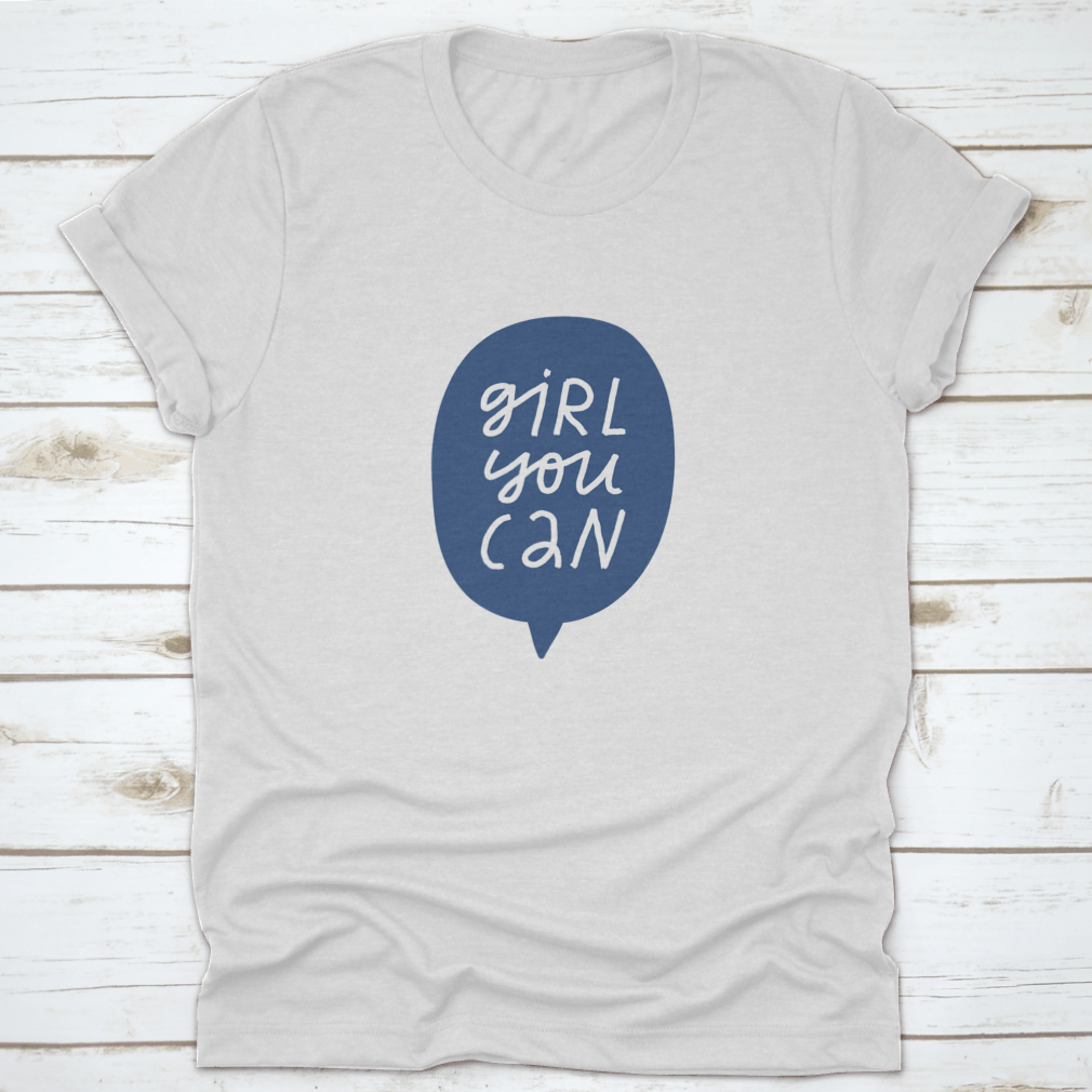 A stylish t-shirt featuring minimalist hand-drawn lettering in a blue speech bubble that reads 'Girl You Can', showcasing a casual and empowering design.