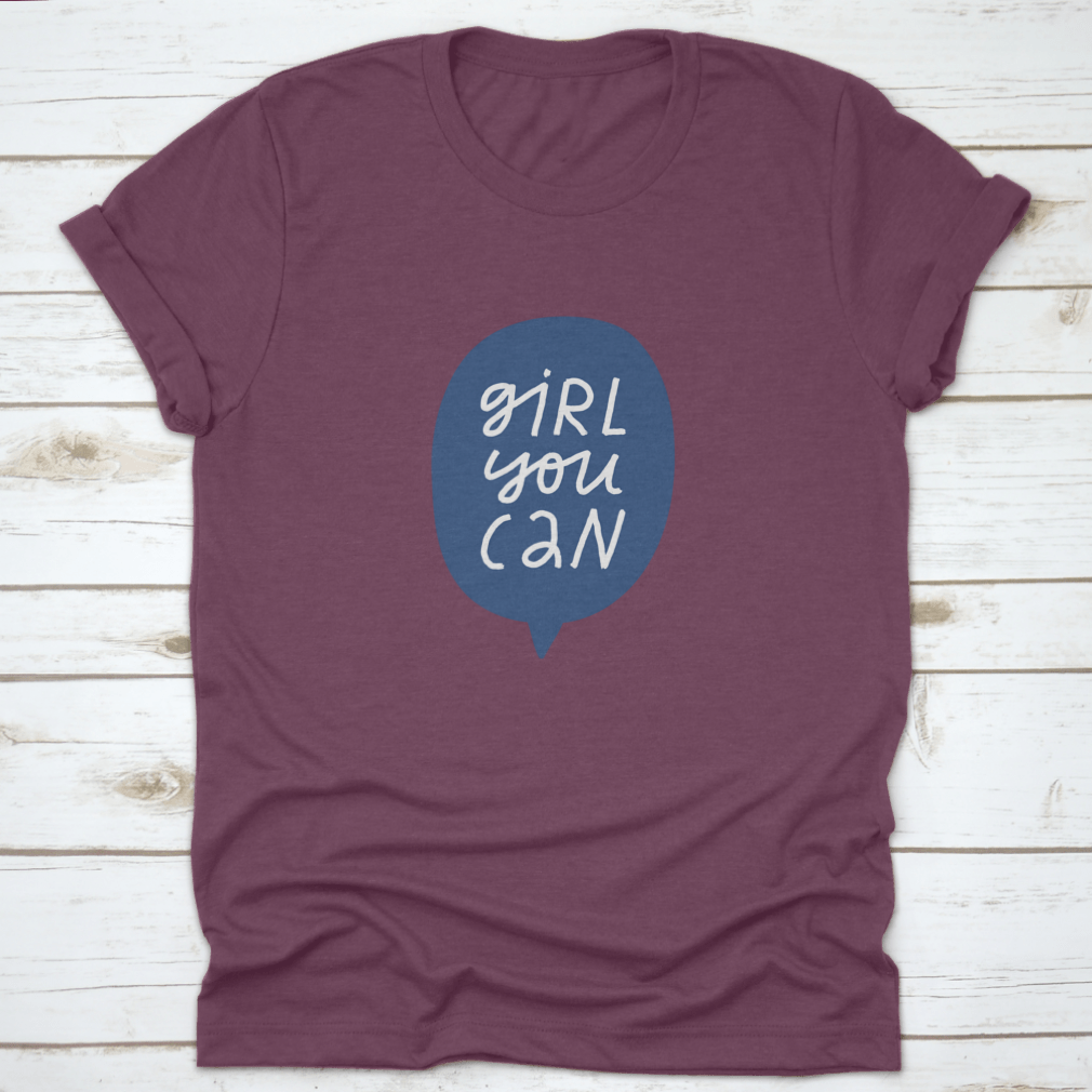 A stylish t-shirt featuring minimalist hand-drawn lettering in a blue speech bubble that reads 'Girl You Can', showcasing a casual and empowering design.