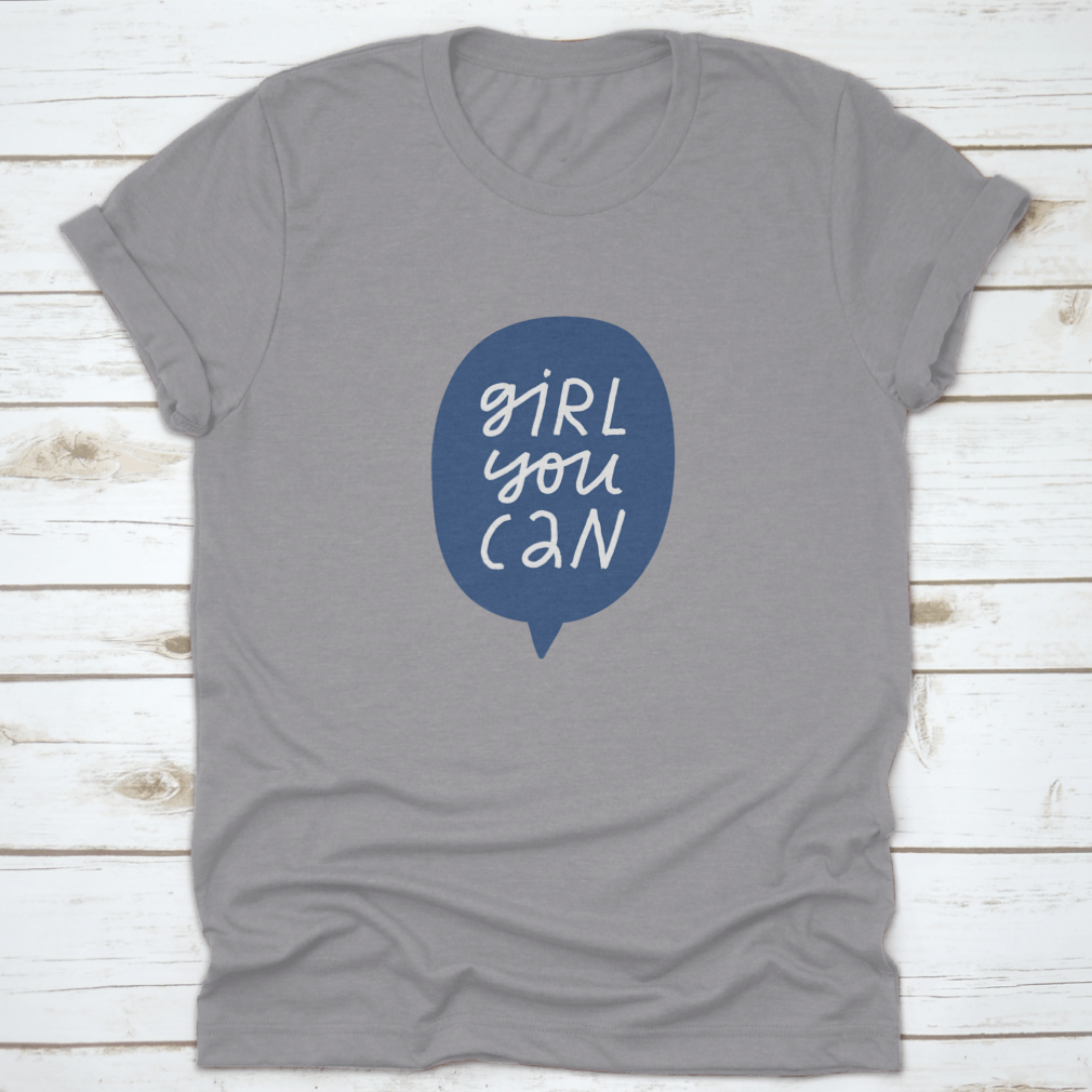 A stylish t-shirt featuring minimalist hand-drawn lettering in a blue speech bubble that reads 'Girl You Can', showcasing a casual and empowering design.